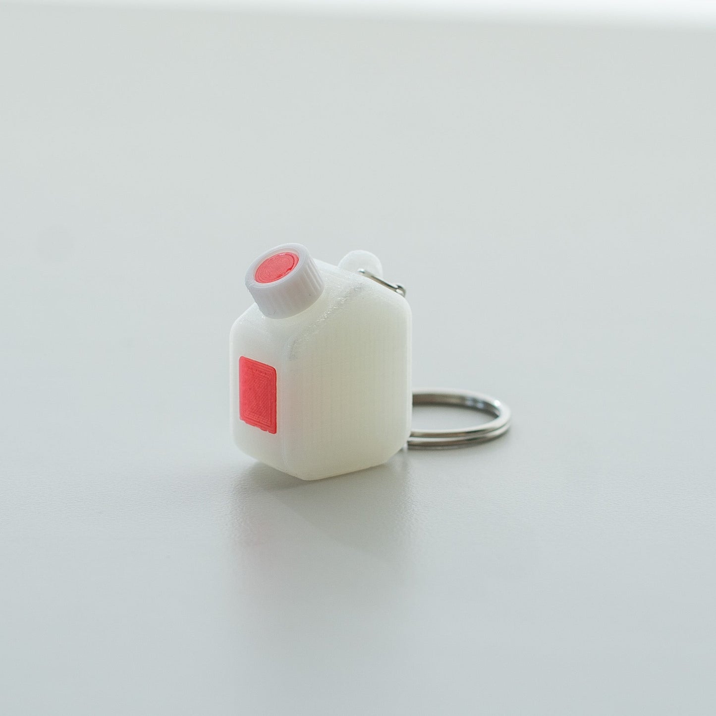 Miniature clear media bottle keychain with a white and red cap