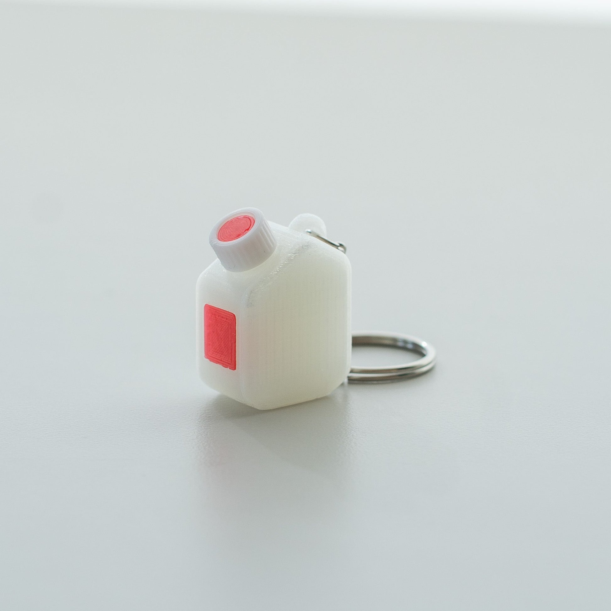 Miniature clear media bottle keychain with a white and red cap