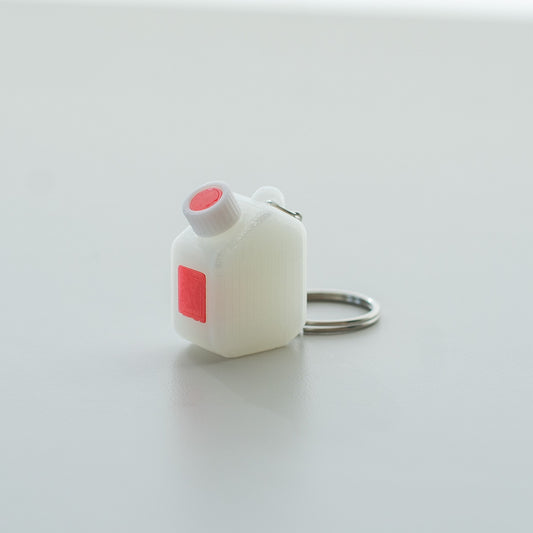 Miniature clear media bottle keychain with a white and red cap