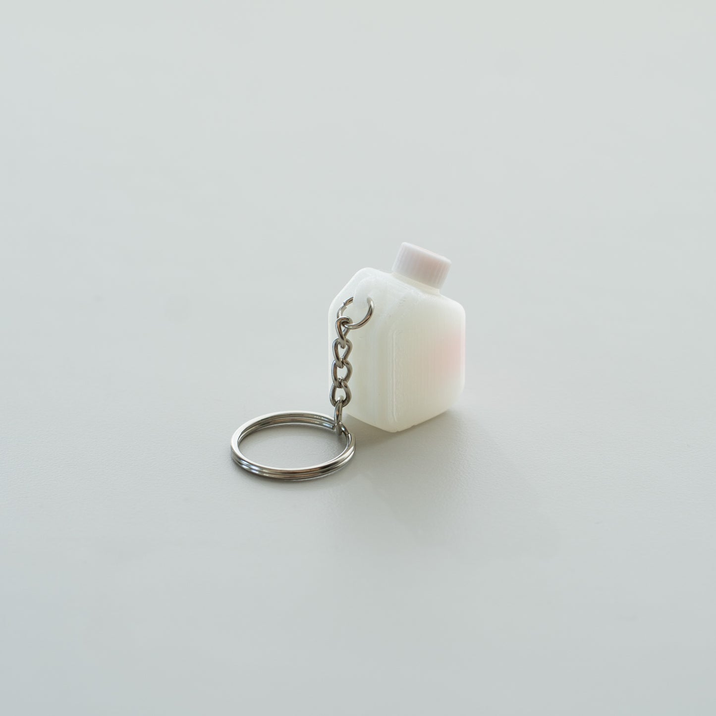 Miniature clear media bottle keychain with a white and red cap