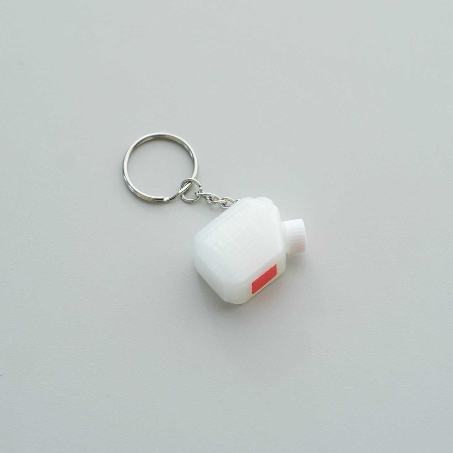 Miniature clear media bottle keychain with a white and red cap